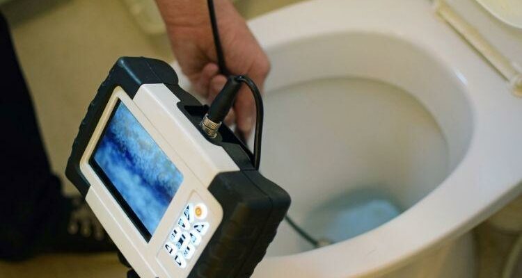 Plumber using a tool to fix the toilets
